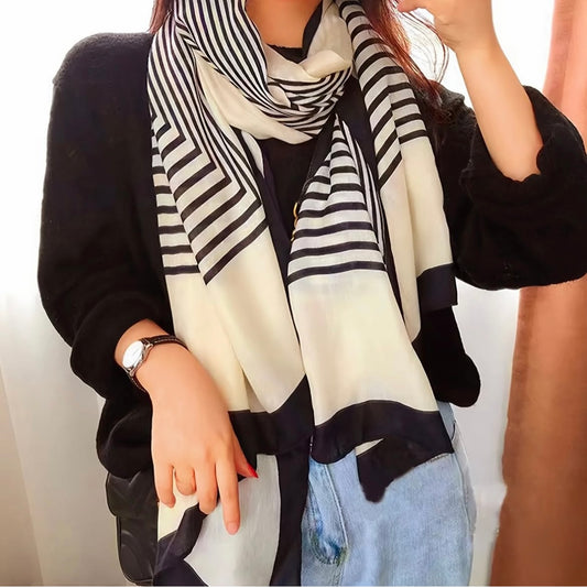 Person wearing a black and white striped scarf with a plain background