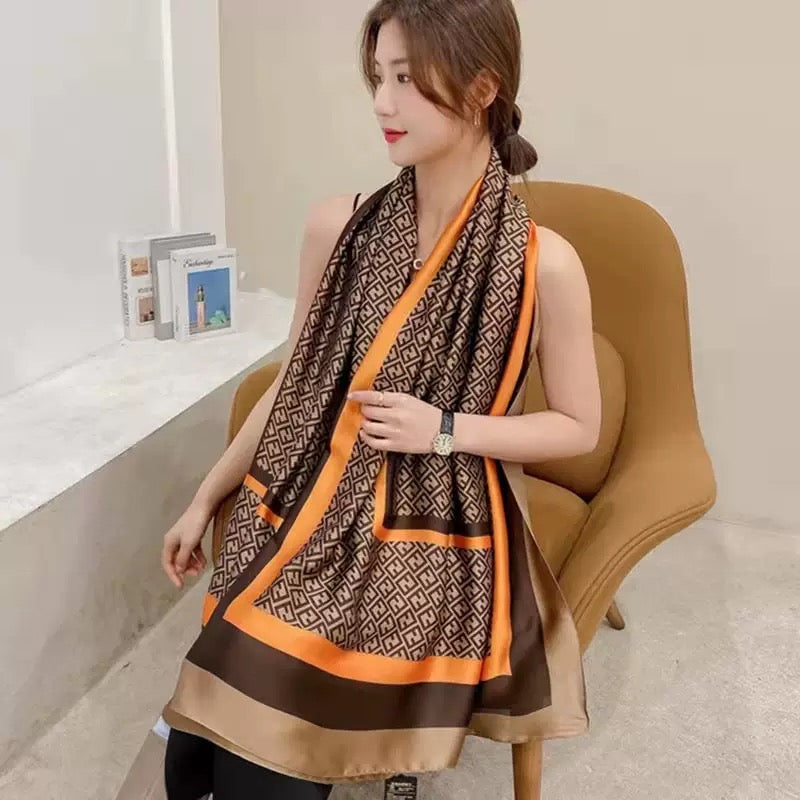 Woman wearing geometric print silk scarf with black outfit - brown beige orange scarf styling