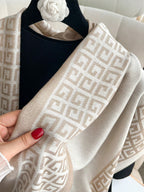 Beige patterned scarf held by a hand with red nail polish