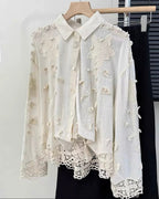 White embroidered blouse on a hanger against a white background