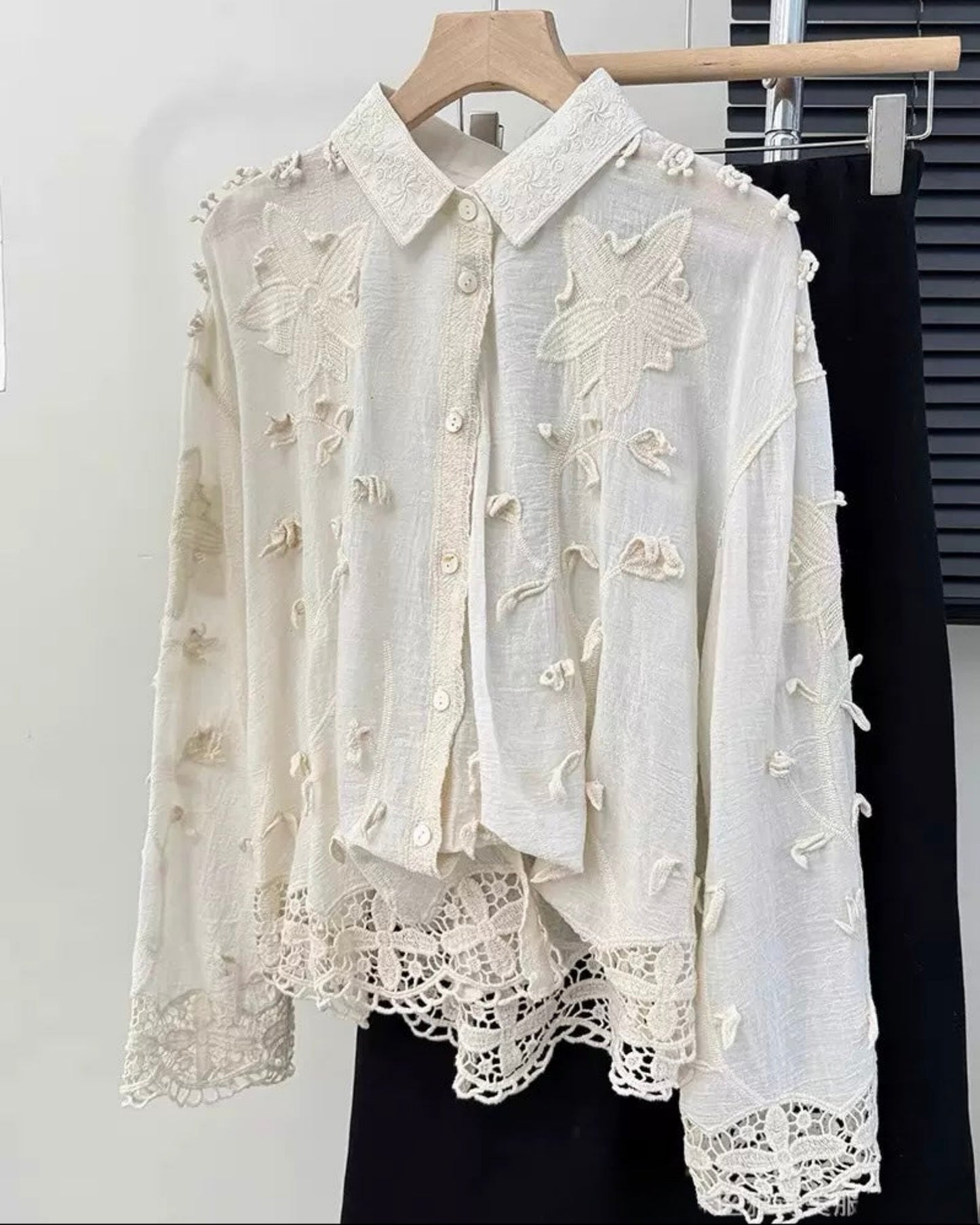 White embroidered blouse on a hanger against a white background