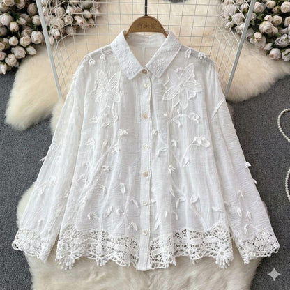 White lace blouse on a hanger with floral decorations in the background