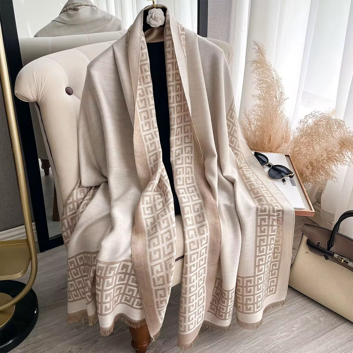 Beige patterned scarf draped over a chair with a neutral background
