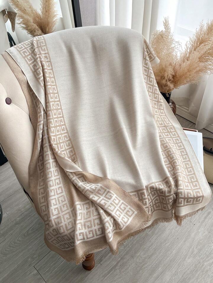 Beige patterned throw blanket draped over a chair with decorative elements in the background.