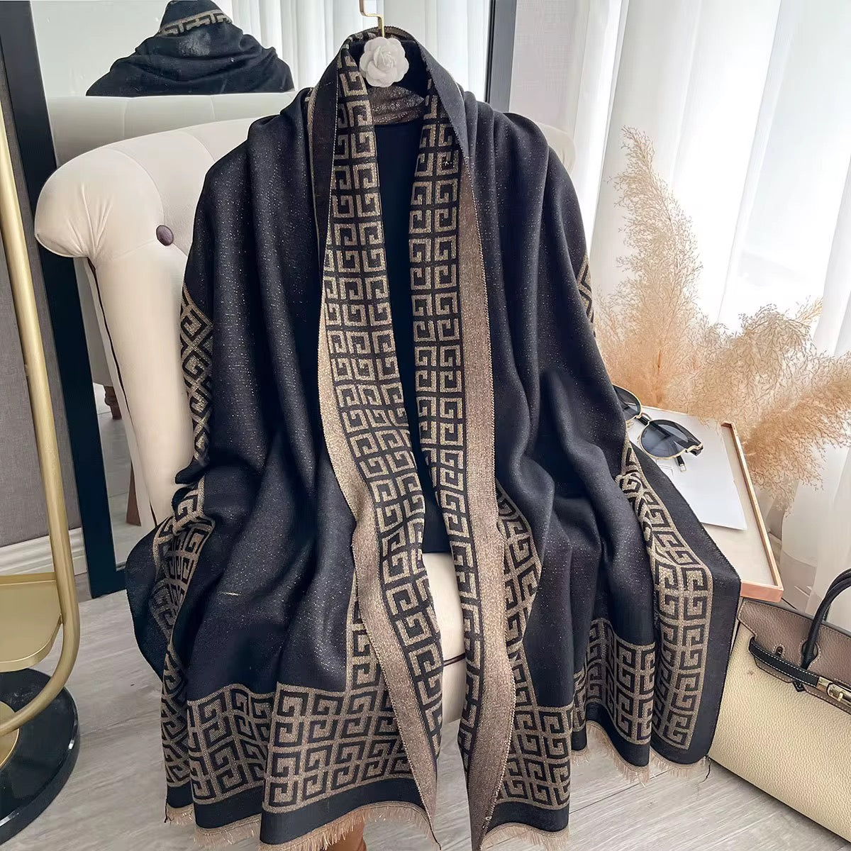 Black patterned scarf draped over a chair with a neutral background