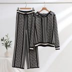 A hooded co ord set displayed on hangers, featuring a geometric pattern with black and white colors. The set includes a long-sleeved top and wide-leg pants.