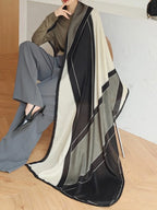 Person wearing a long, patterned scarf with a neutral background