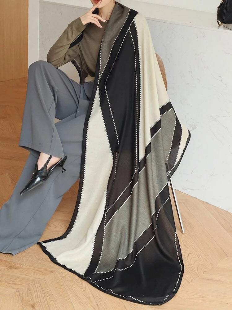Person wearing a long, patterned scarf with a neutral background