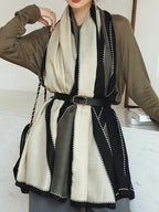 Person wearing a black and white patterned scarf with a brown cardigan.