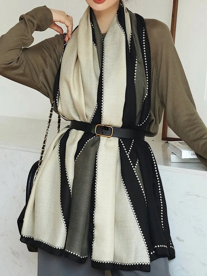 Person wearing a black and white patterned scarf with a brown cardigan.