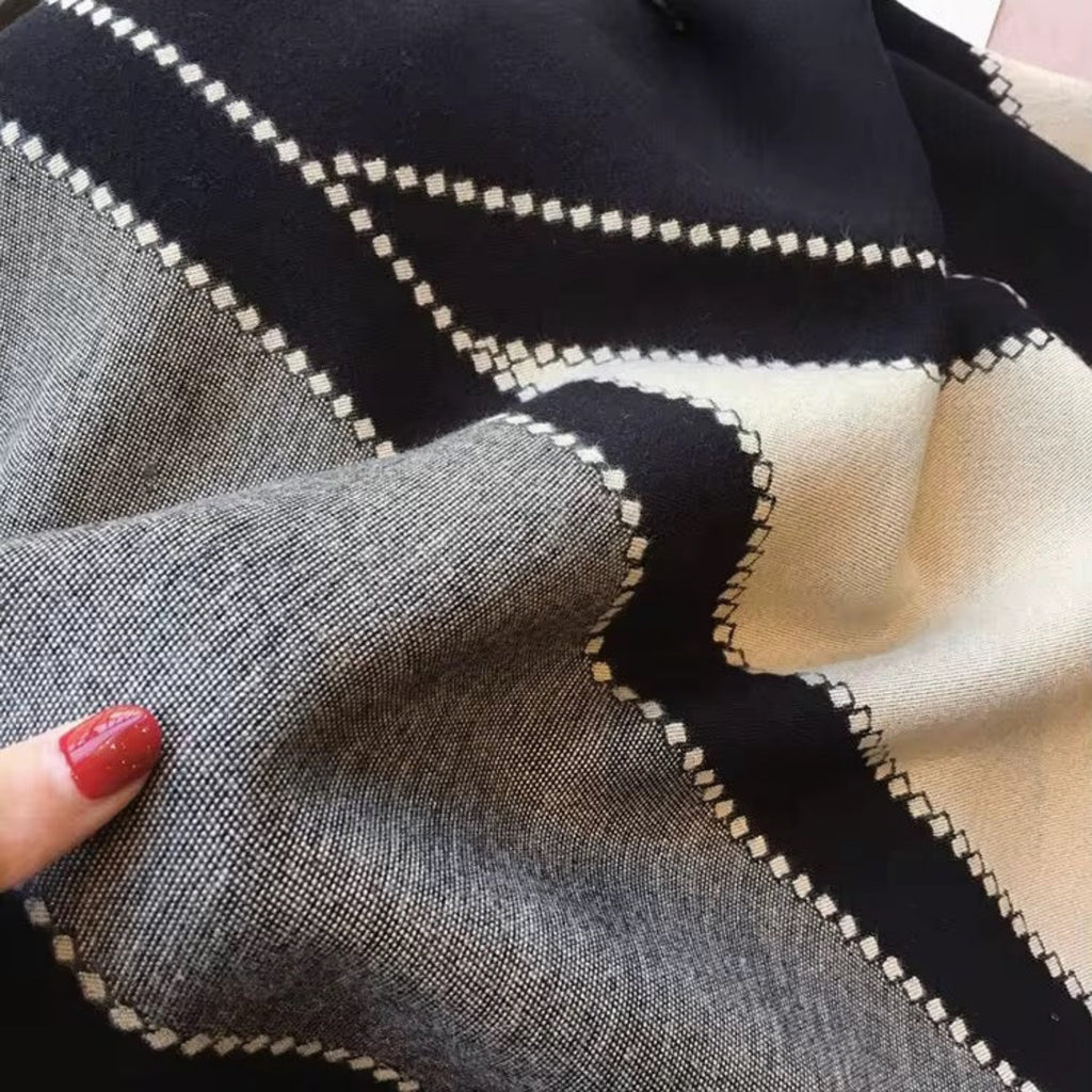 Close-up of fabric with geometric pattern, held by a hand with red nail polish.