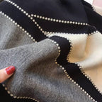 Close-up of fabric with geometric pattern, held by a hand with red nail polish.