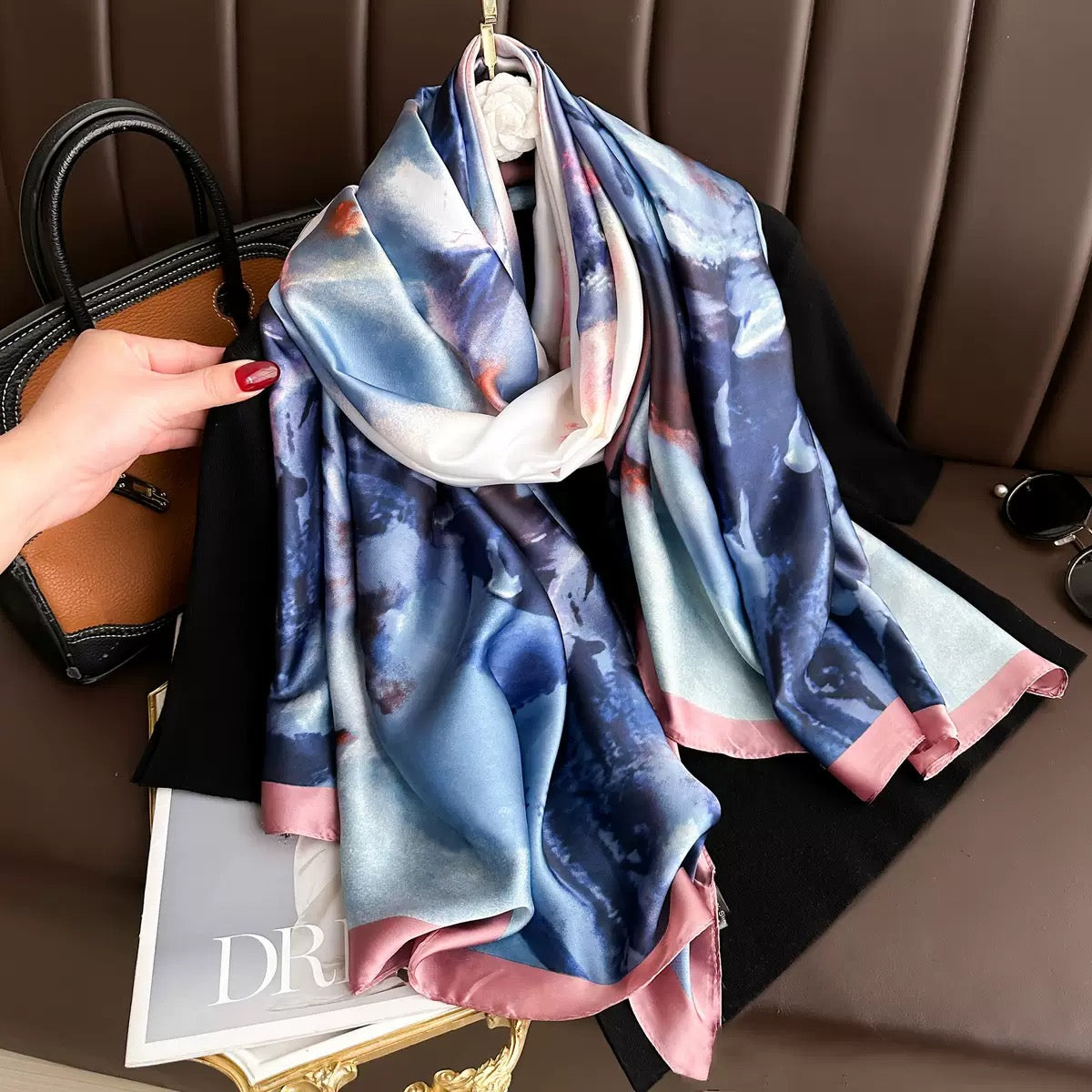 Colorful scarf with floral pattern draped over a handbag on a brown surface