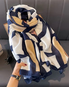 Colorful geometric patterned scarf held by a hand on a dark surface.