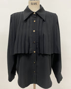 Black pleated cape collar shirt on mannequin - front view showing vertical pleated detail and collar