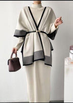Person wearing a stylish outfit with a white and black cardigan and holding a purple handbag.