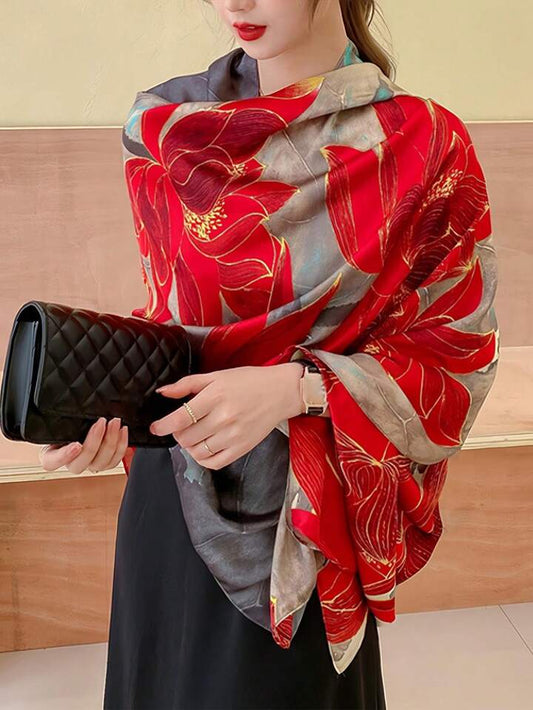 A person wearing a red and gray floral patterned silk scarf with a black handbag and a dark dress.