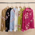 Colorful floral shirts on hangers against a gray wall