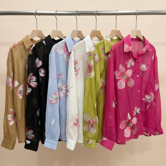 Colorful floral shirts on hangers against a gray wall