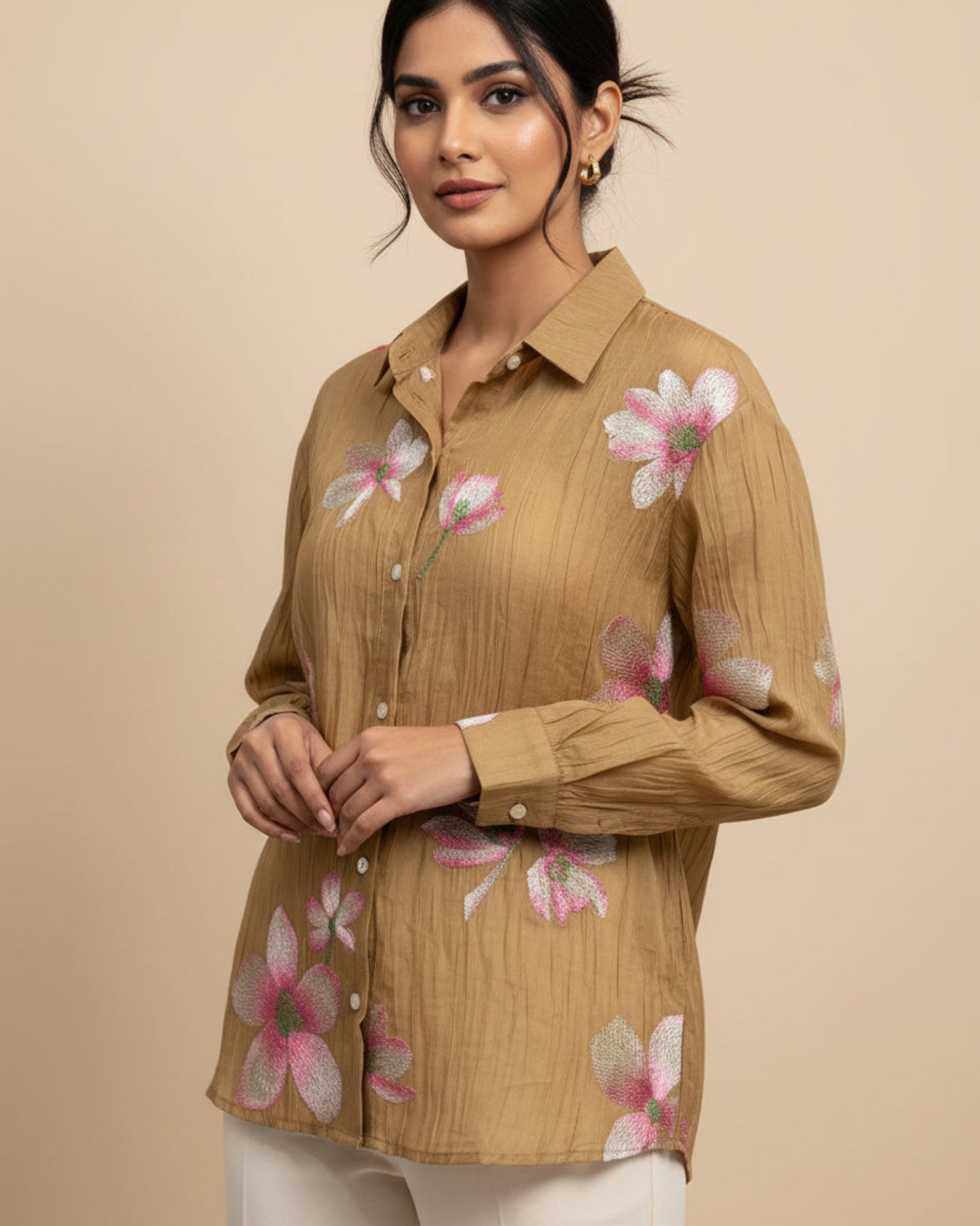 Brown shirt with floral patterns on a hanger against a gray background