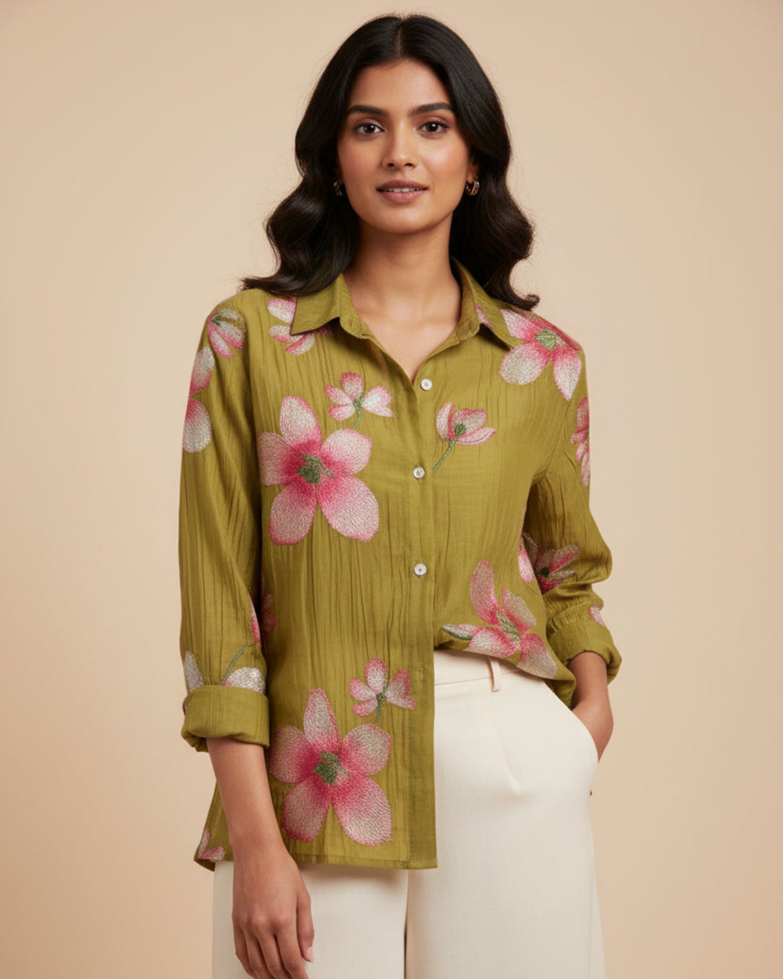 Green shirt with pink floral patterns on a wooden hanger against a gray wooden background