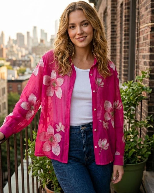 Woman wearing a pink floral shirt on a rooftop with cityscape in the background