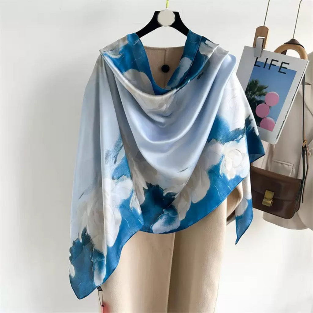 Blue and white patterned scarf draped over a mannequin with a magazine and handbag in the background.