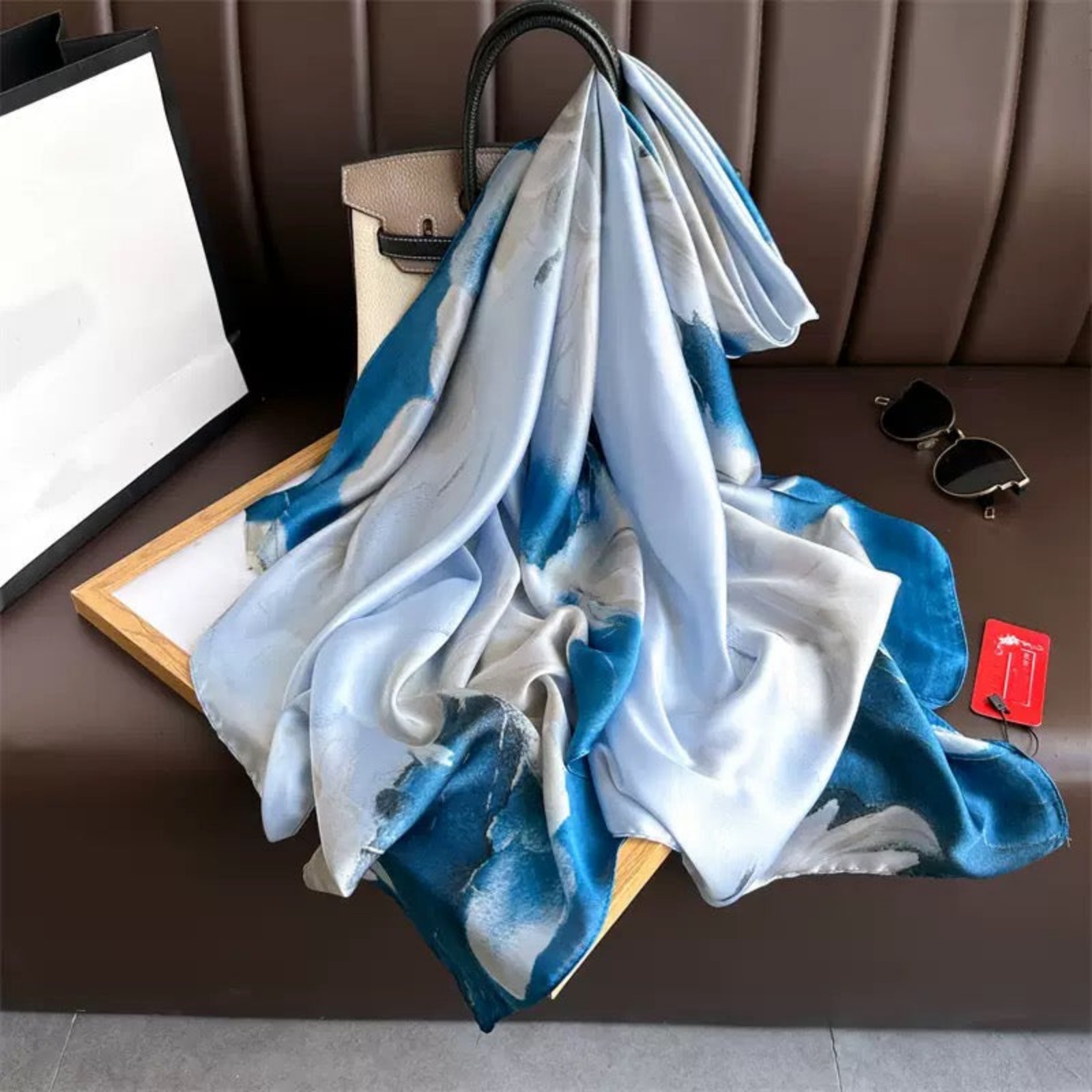 Blue and white scarf draped over a chair with a handbag and sunglasses nearby.