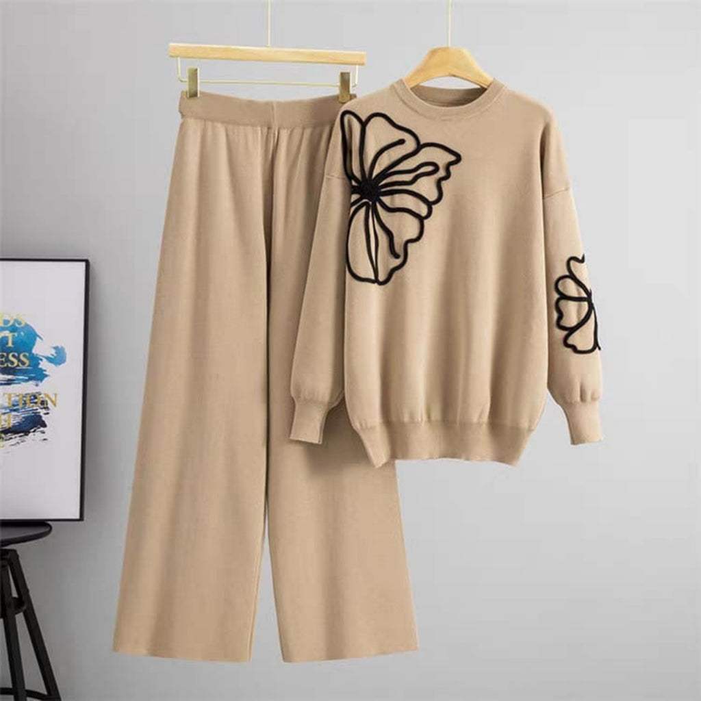 Beige sweater and pants set with butterfly design on a hanger against a gray background.