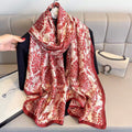 Red and white patterned scarf draped over a black jacket on a light gray couch.