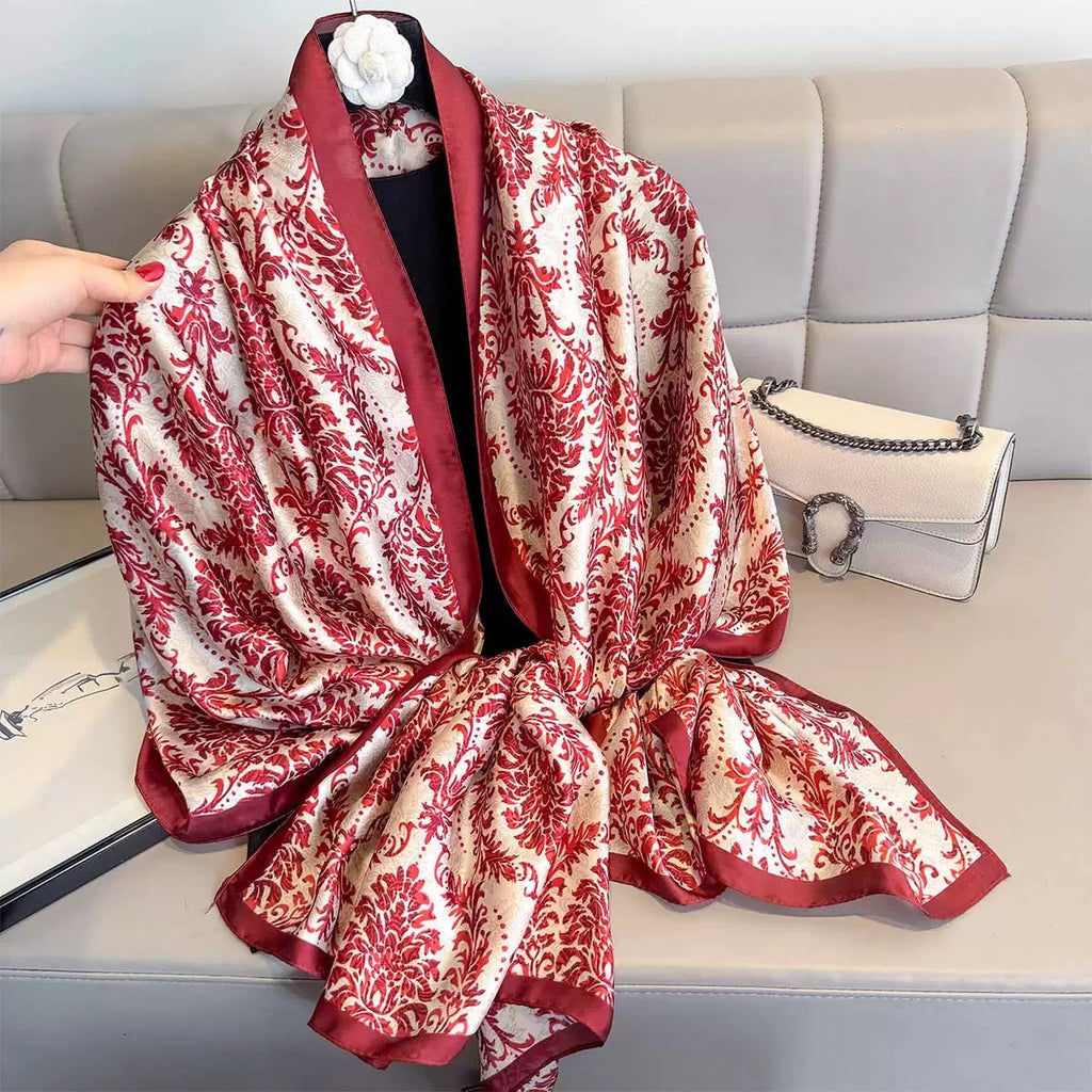 Red and white patterned scarf draped over a sofa with a handbag beside it.