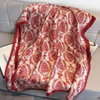 Red and white patterned scarf draped over a surface with a magazine underneath.