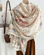 Floral-patterned scarf draped over a chair with a handbag beside it.