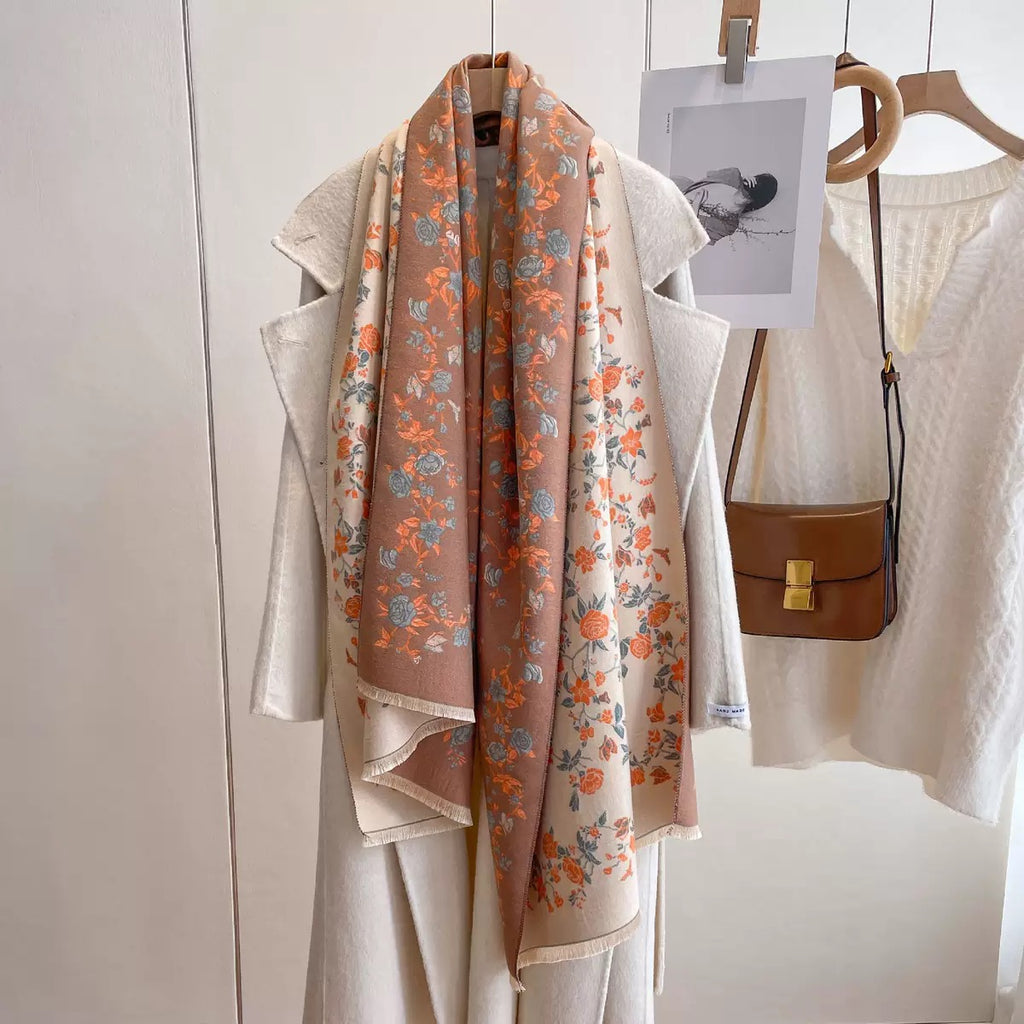 Floral scarf draped over a coat with a handbag on a white background