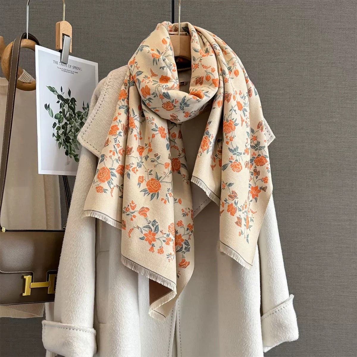 Floral scarf draped over a jacket with a handbag and plant in the background