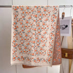 Floral patterned towel hanging on a rack with a brown bag and photo in the background.