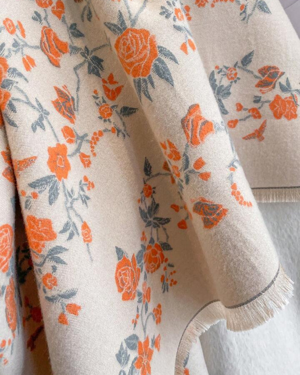 Floral patterned fabric with orange and blue flowers on a beige background