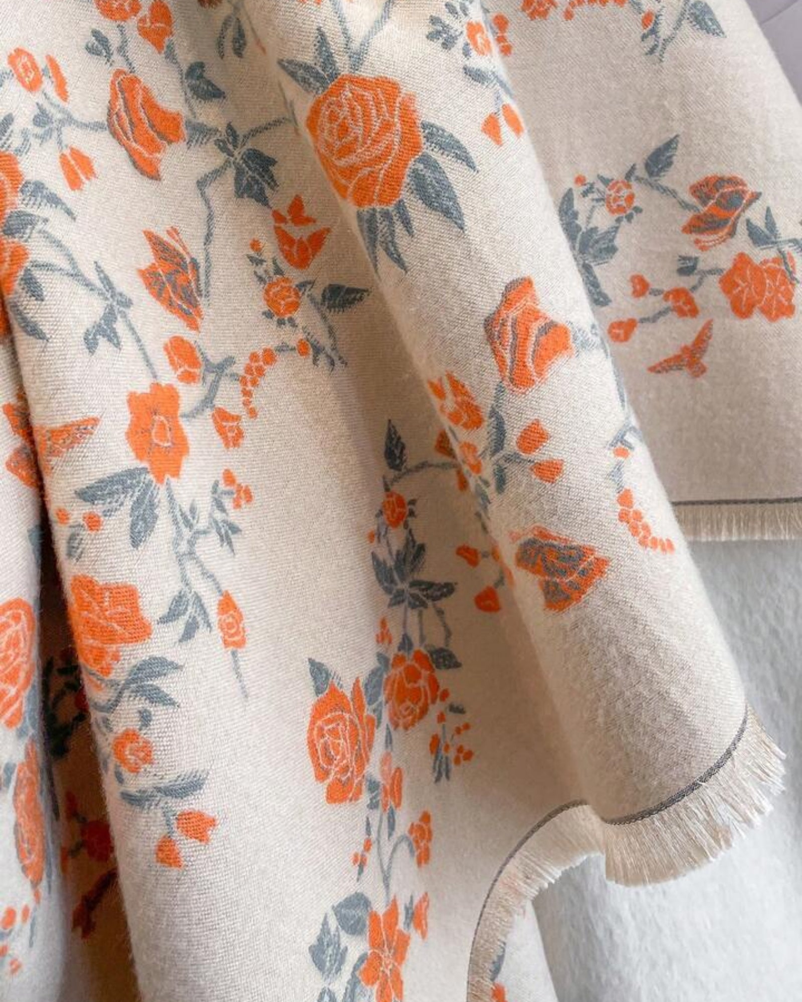 Floral patterned fabric with orange and blue flowers on a beige background
