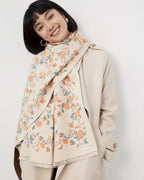 Woman wearing a beige coat with a floral pattern over a white background