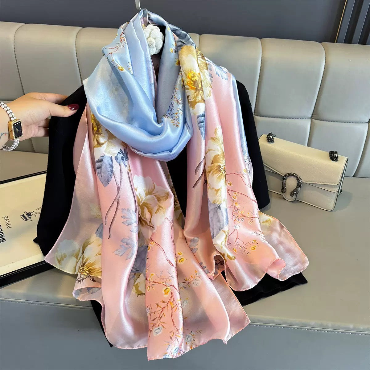 Floral patterned scarf draped over a couch with a handbag in the background