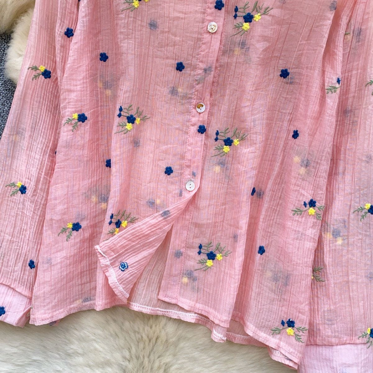 Pink fabric with floral embroidery on a textured surface