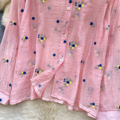 Pink fabric with floral embroidery on a textured surface
