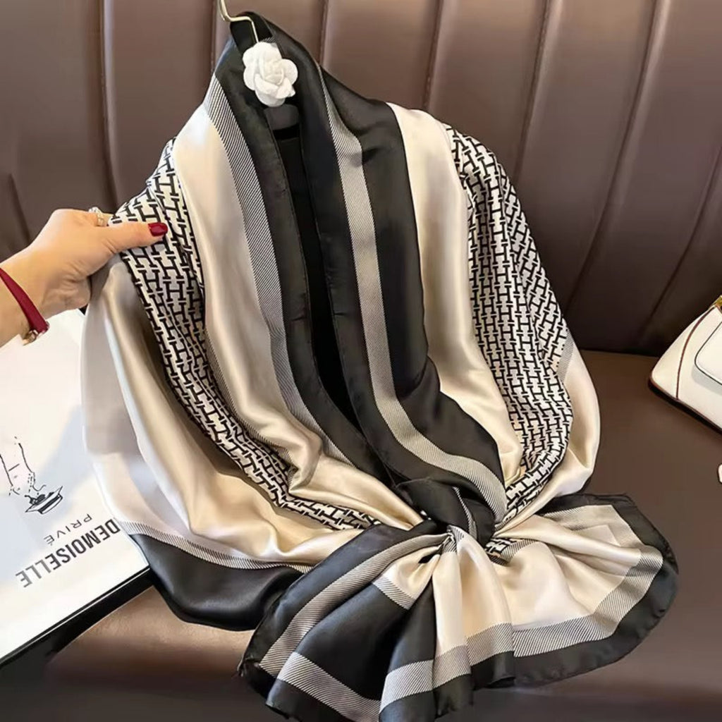 Black and white patterned scarf held by a hand on a brown surface