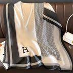 Black and white patterned scarf with a letter 'H' on a brown surface