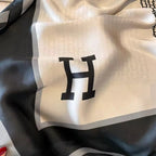 White fabric with a black 'H' logo on a dark background