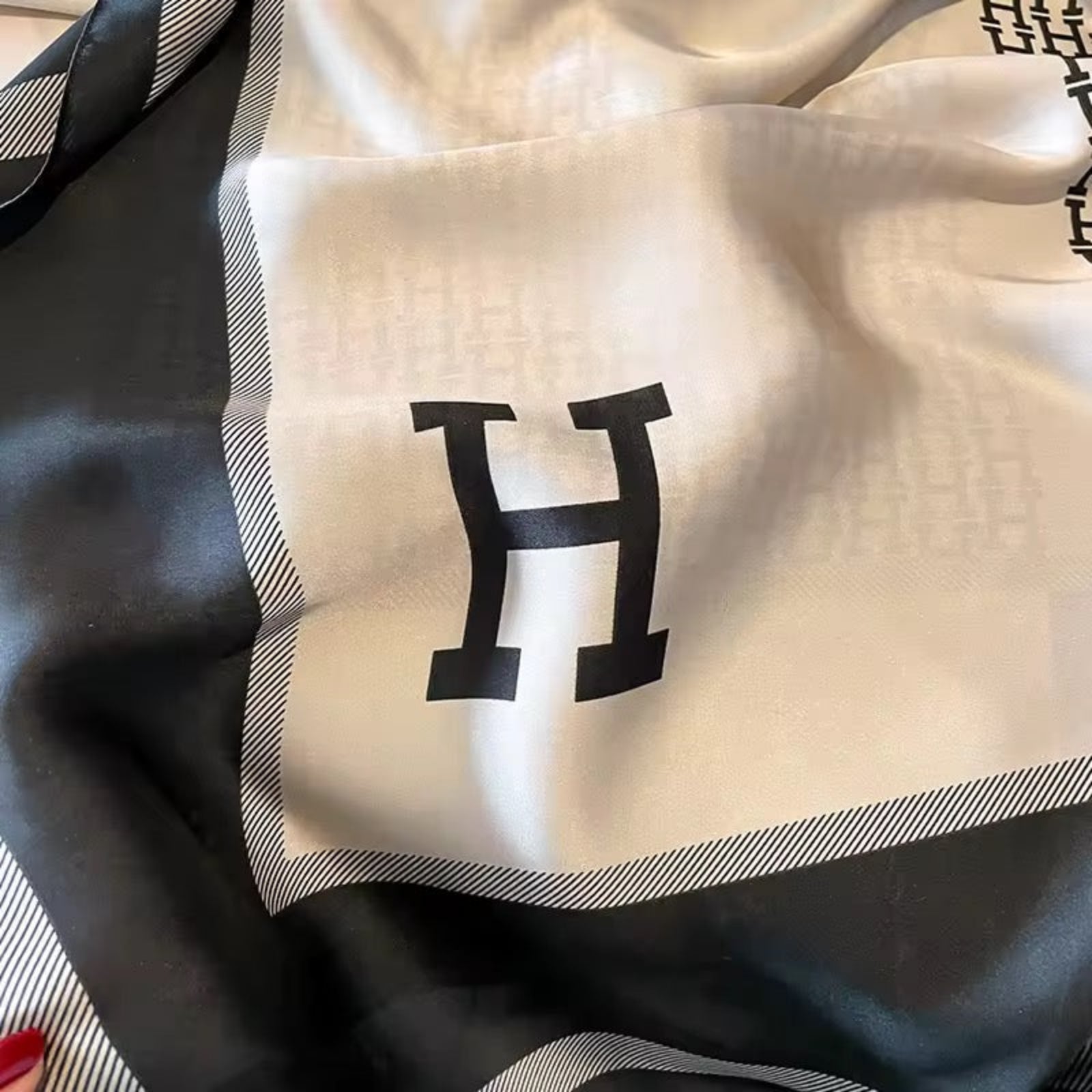 White fabric with a black 'H' logo on a dark background