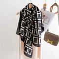 Black and white geometric scarf on a mannequin with a brown handbag in the background.