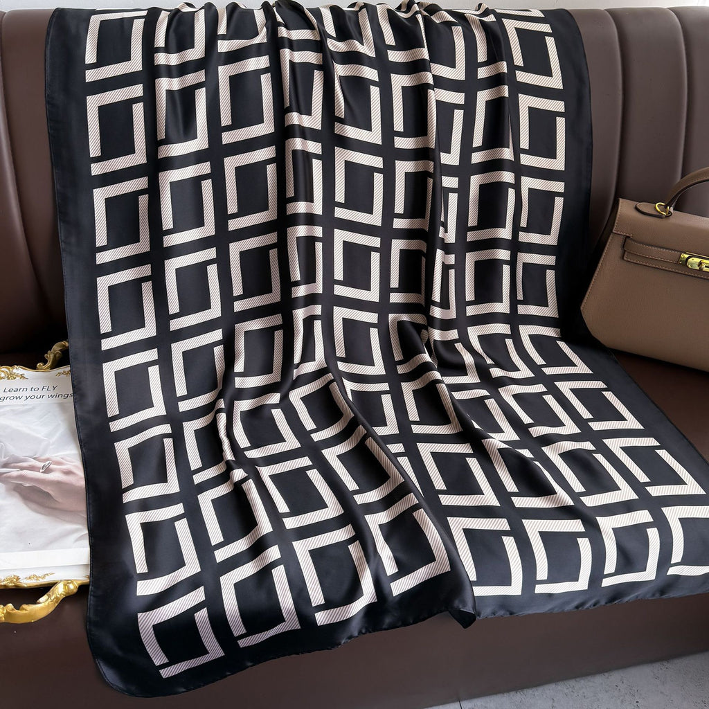 Black and white geometric patterned blanket draped over a brown sofa.