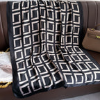 Black and white geometric patterned blanket draped over a brown sofa.