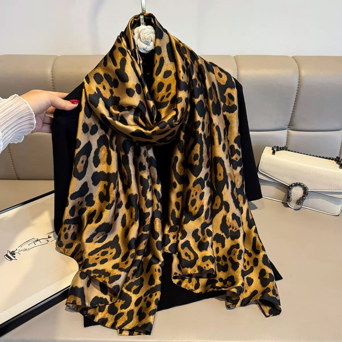 Leopard print scarf draped over a black garment against a neutral background